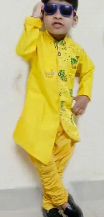 Person in vibrant yellow traditional attire with sunglasses.