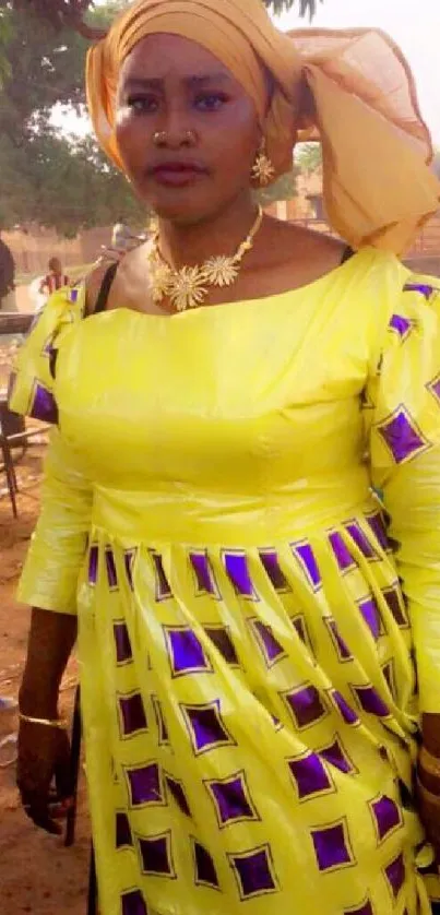 Woman in vibrant yellow traditional attire outdoors.