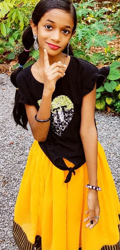 Young girl in yellow skirt outdoors with greenery.