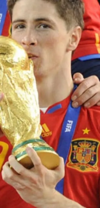 Football player in red jersey kissing trophy in celebration.