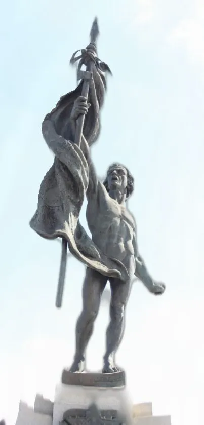 Statue holding flag under a bright blue sky, symbolizing victory.