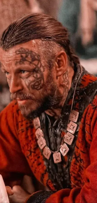 Viking warrior with tattoos in red attire, holding a cup.