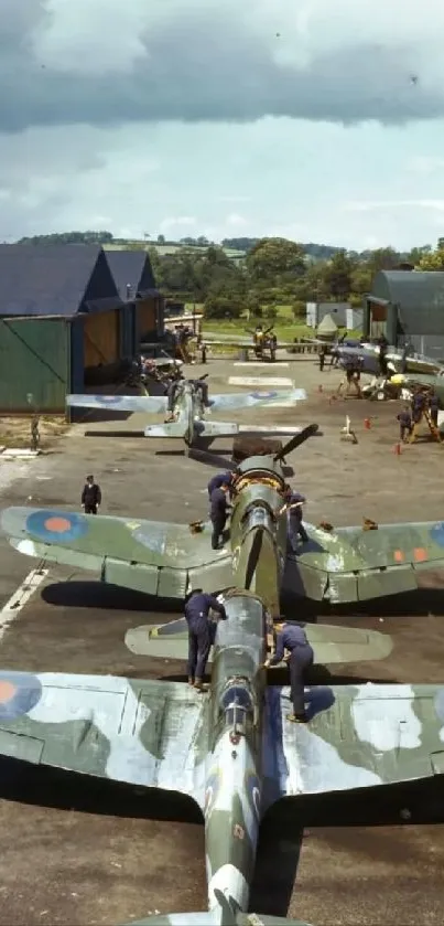 A line of vintage military airplanes at an airfield with scenic background.