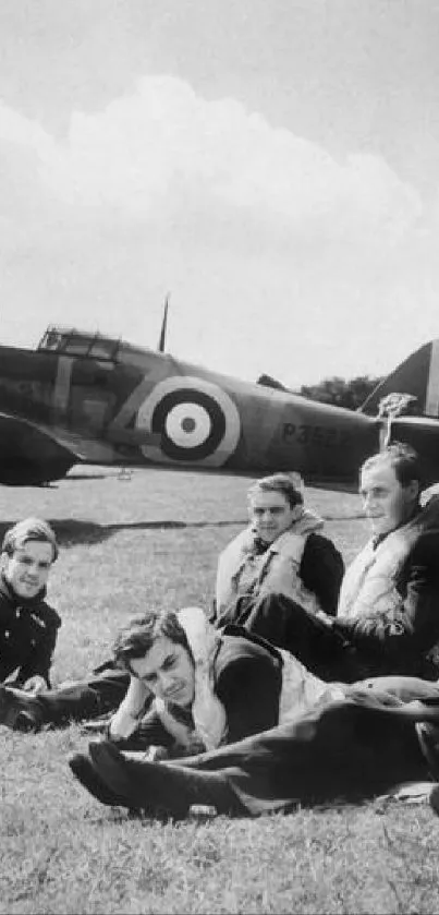 Vintage WWII pilots relax by aircraft, black and white.