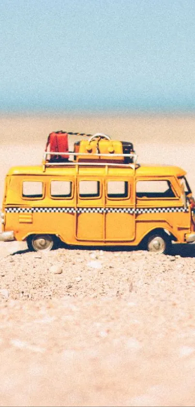 Yellow toy bus on sandy beach with clear blue sky.