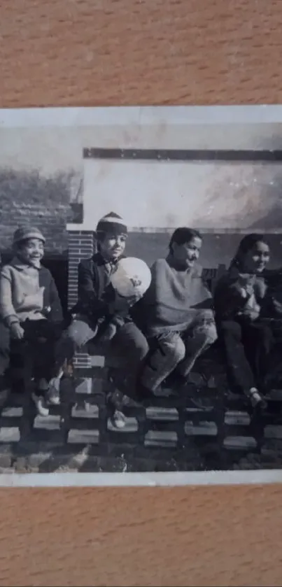 Black and white vintage photo of children sitting on a wall.