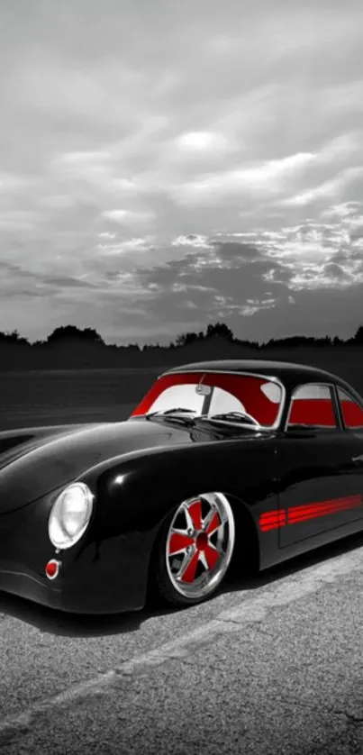 Vintage black car with red accents against a cloudy sky backdrop.