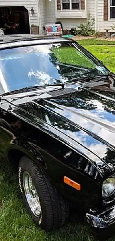 Vintage black car parked on green lawn in front of house.