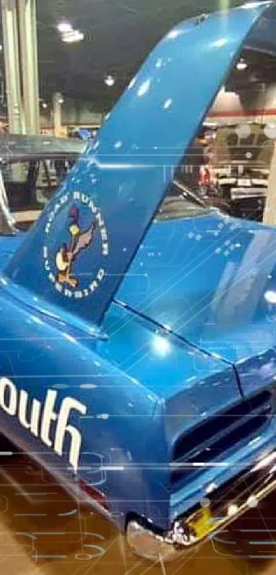 A vintage blue Plymouth muscle car with prominent wing in a museum setting.