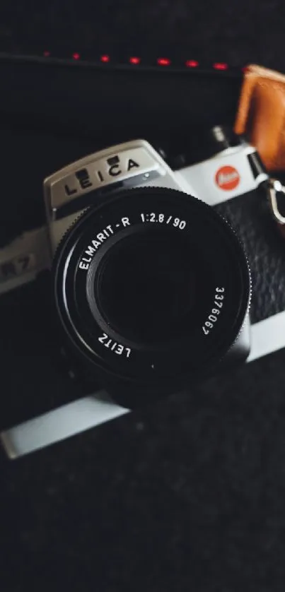 Stylish vintage camera with leather strap on a dark background.