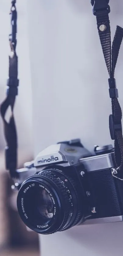 A vintage camera hanging on a strap with soft blue hues.