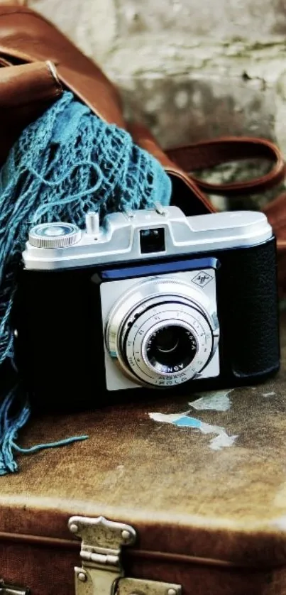 Vintage camera on a suitcase with blue scarf.