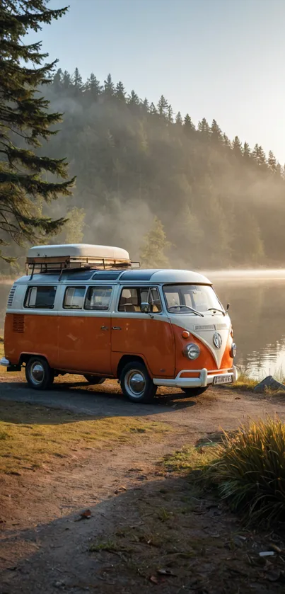 Vintage orange camper van by a misty lakeside with forest backdrop.