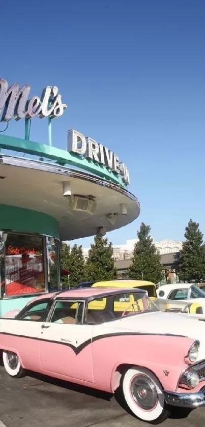 Vintage pink car parked by a retro diner under a clear blue sky.
