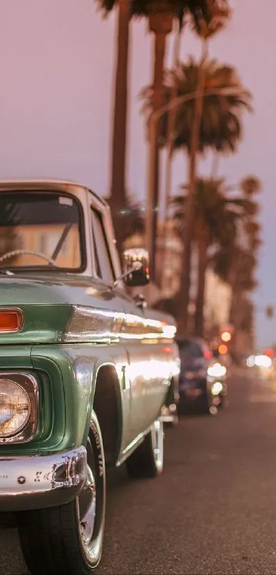 Vintage green car with palm trees at sunset on a city road.