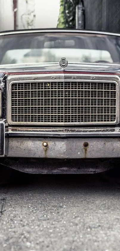 Close-up front view of a vintage car with a metal grille on an urban street.