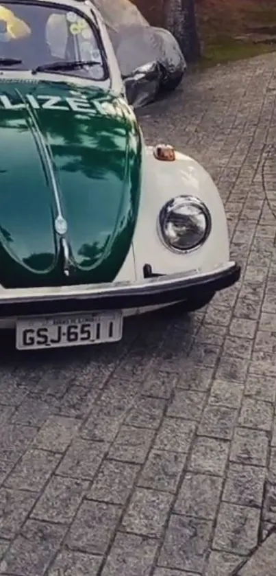 Vintage green car on cobblestone path with police insignia.