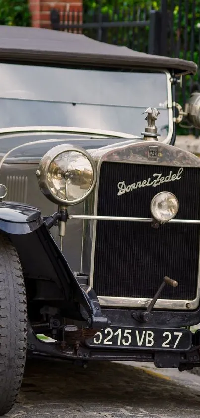 Vintage car parked on cobbled street with classic design.