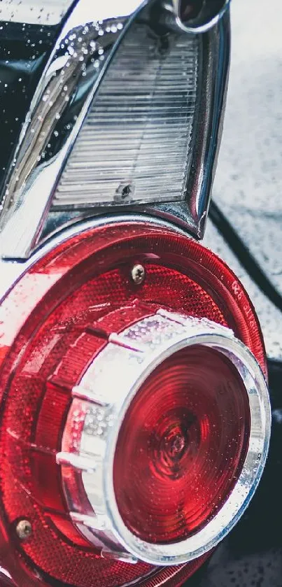 Close-up of a vintage car's red tail light with chrome details.