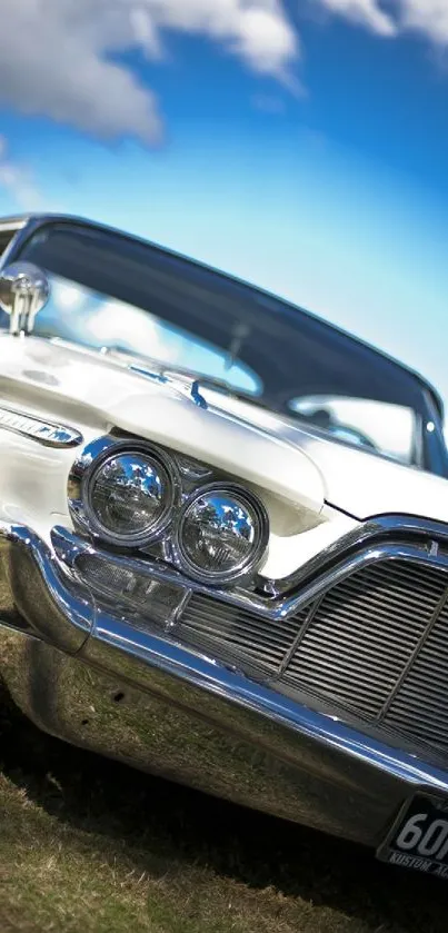 A vintage car with chrome details parked under a blue sky.