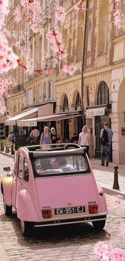 Pink vintage car on a blossom-lined street.