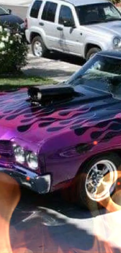 Vintage muscle car with purple flames parked in driveway.