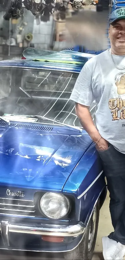 Man stands by classic blue car in a rustic workshop setting.