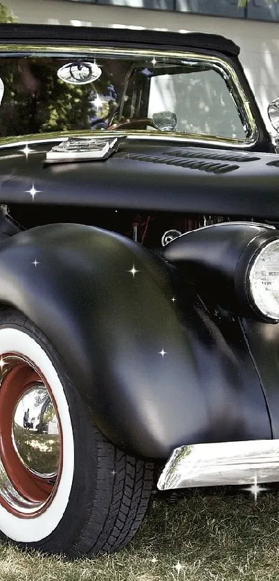 Black vintage classic car parked on grass under a tree.