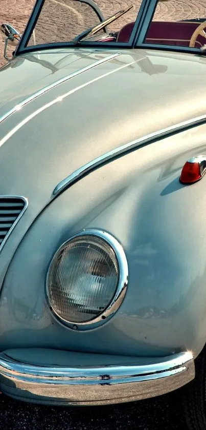 Vintage convertible car with silver metallic finish on pavement.
