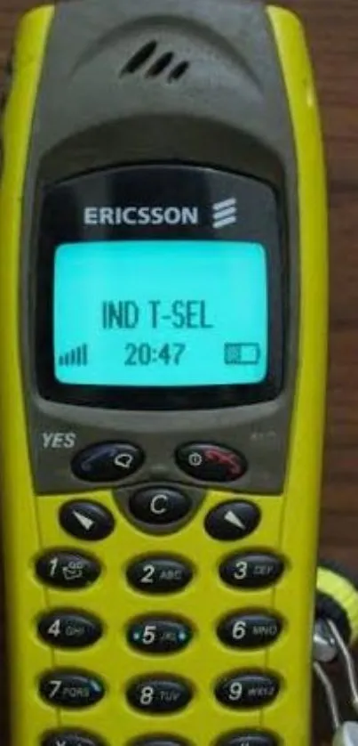 Yellow Ericsson mobile phone on wooden table.