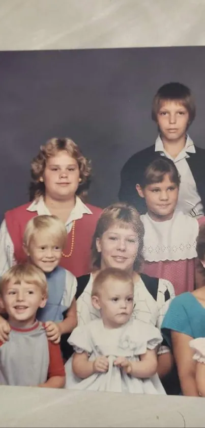 A vintage family portrait featuring children in 1980s attire against a gray backdrop.