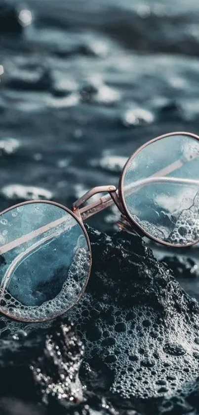 Vintage round glasses on rocky beach in aqua tones.