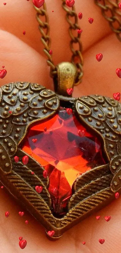 Hand holding a vintage heart pendant with red gemstone.