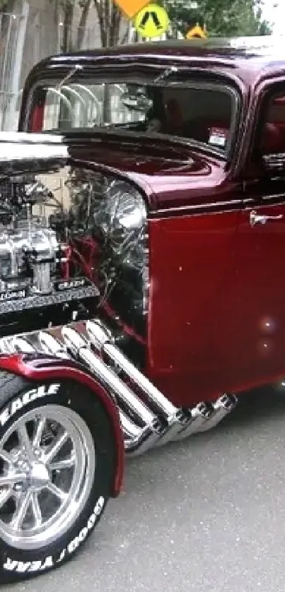 Cherry-red vintage hot rod car with chrome engine on street.