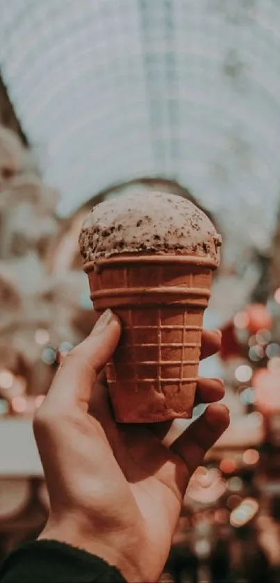 Hand holding an ice cream cone with a blurred vintage background.