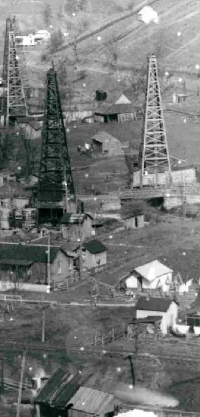 Monochrome image of oil rigs and village buildings in a vintage industrial landscape.