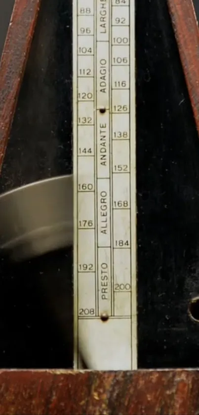 Close-up of a vintage wooden metronome with visible tempo markings.