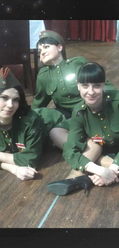 Three women in vintage green military uniforms, posing on wooden floor.