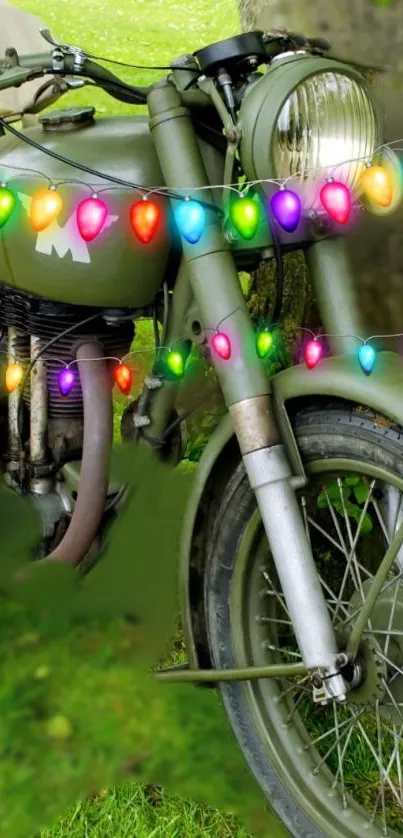 Vintage motorcycle with holiday lights draped over it, set on a grass background.