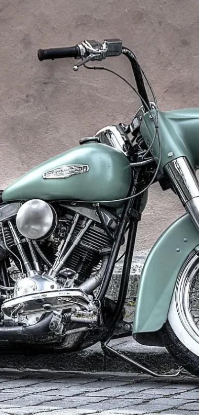 Vintage motorcycle with teal body and chrome details parked on stone pavement.