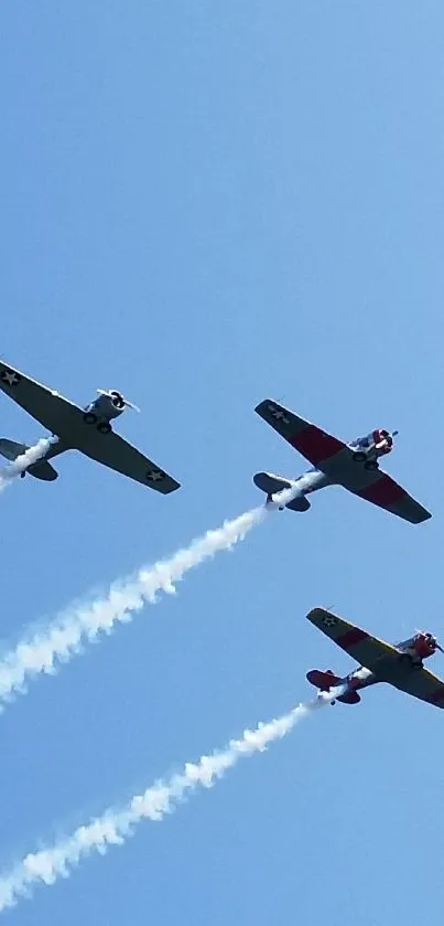 Three vintage airplanes soar in blue sky with contrails.