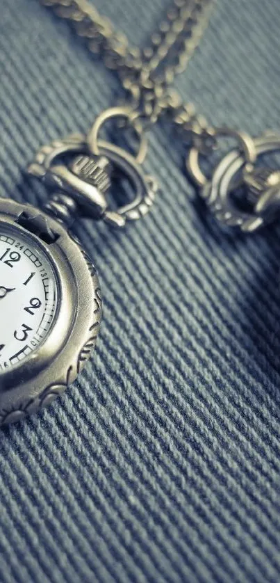 Vintage pocket watch on a textured blue fabric background.