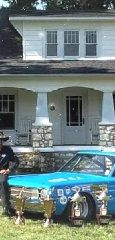 Vintage blue racing car with trophies in front of an old house.