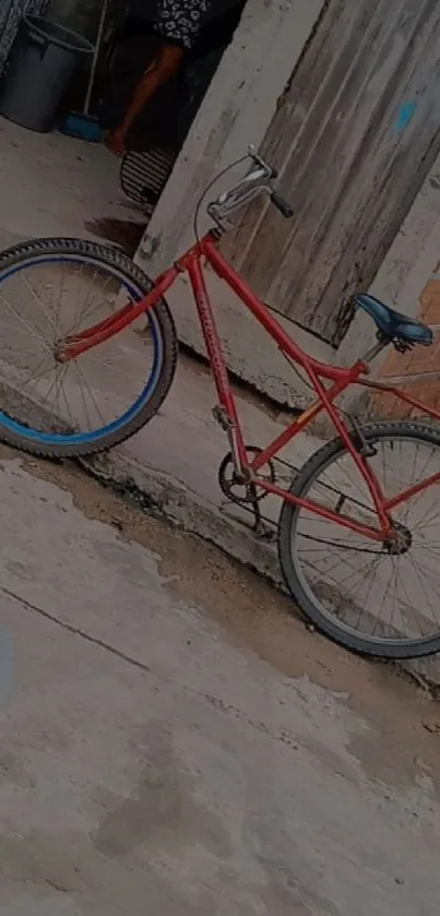 Vintage red bicycle against rustic urban backdrop.