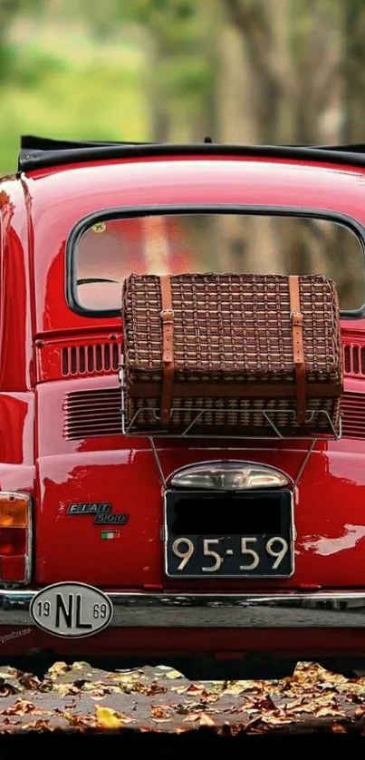 Red vintage car parked on autumn street with wicker basket on trunk.