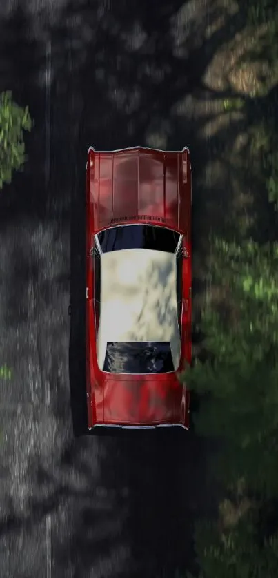 A vintage red car driving on a scenic forest road from an aerial view.