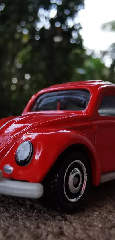 Vintage red toy car against forest backdrop mobile wallpaper.