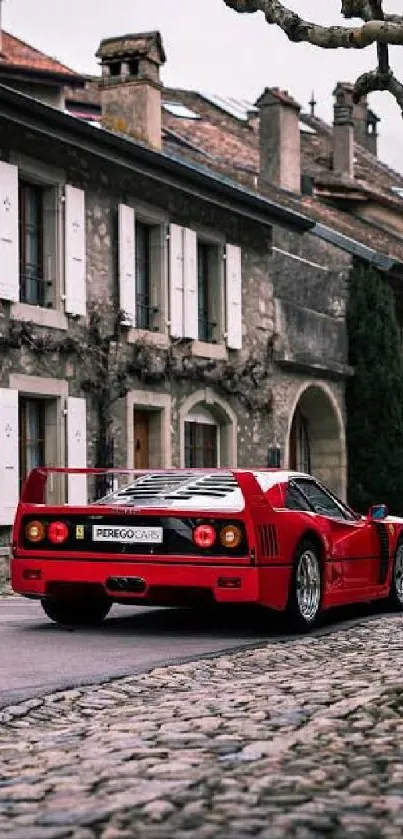 Vintage red sports car on cobblestone street against rustic buildings.