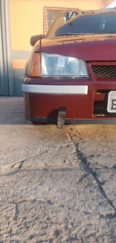 Front view of vintage maroon car on pavement at sunset.