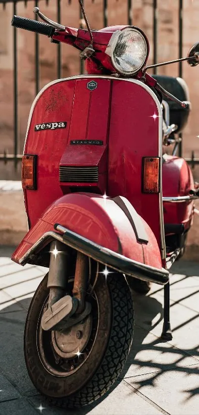 Vintage red Vespa scooter parked in sunlight, casting shadows on the street.